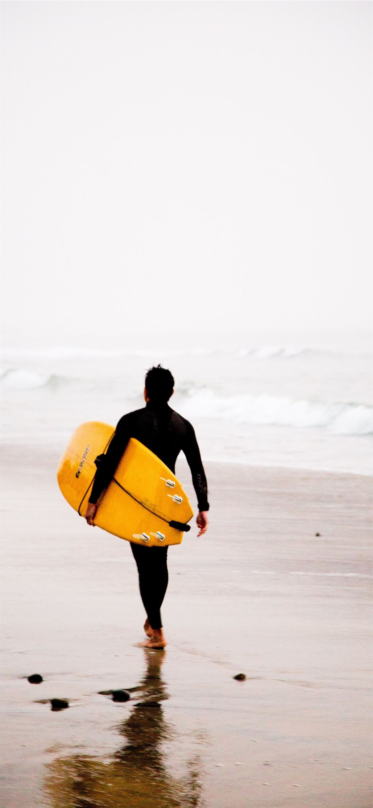 1242x2688 man holding yellow surfboard while walking on iPhone 11 Wallpapers Free Download